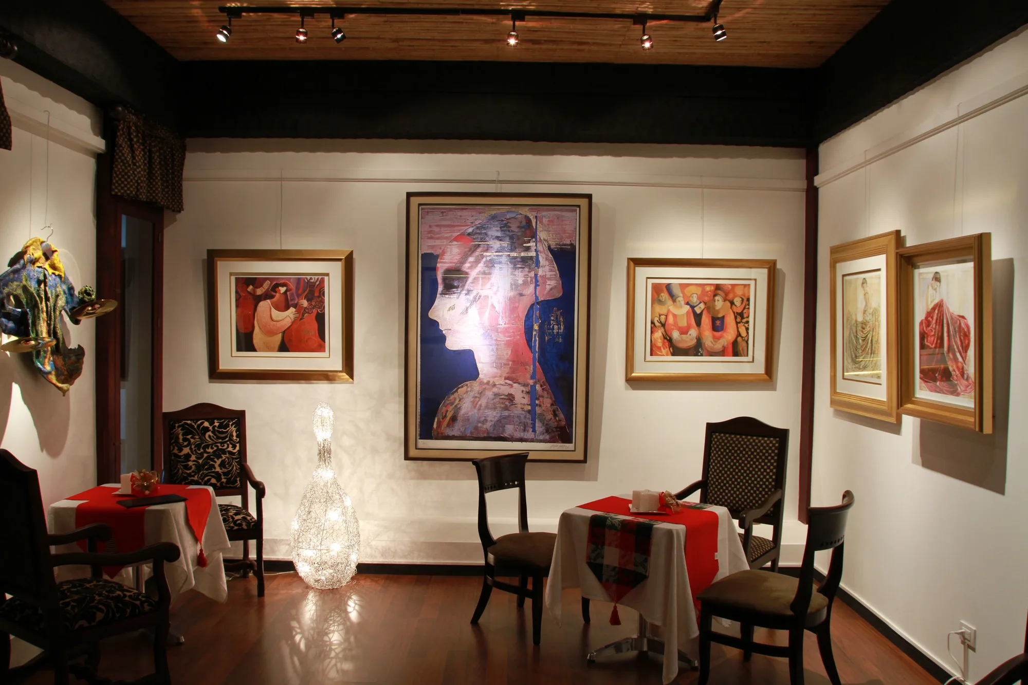 A gallery room with framed paintings on three walls.