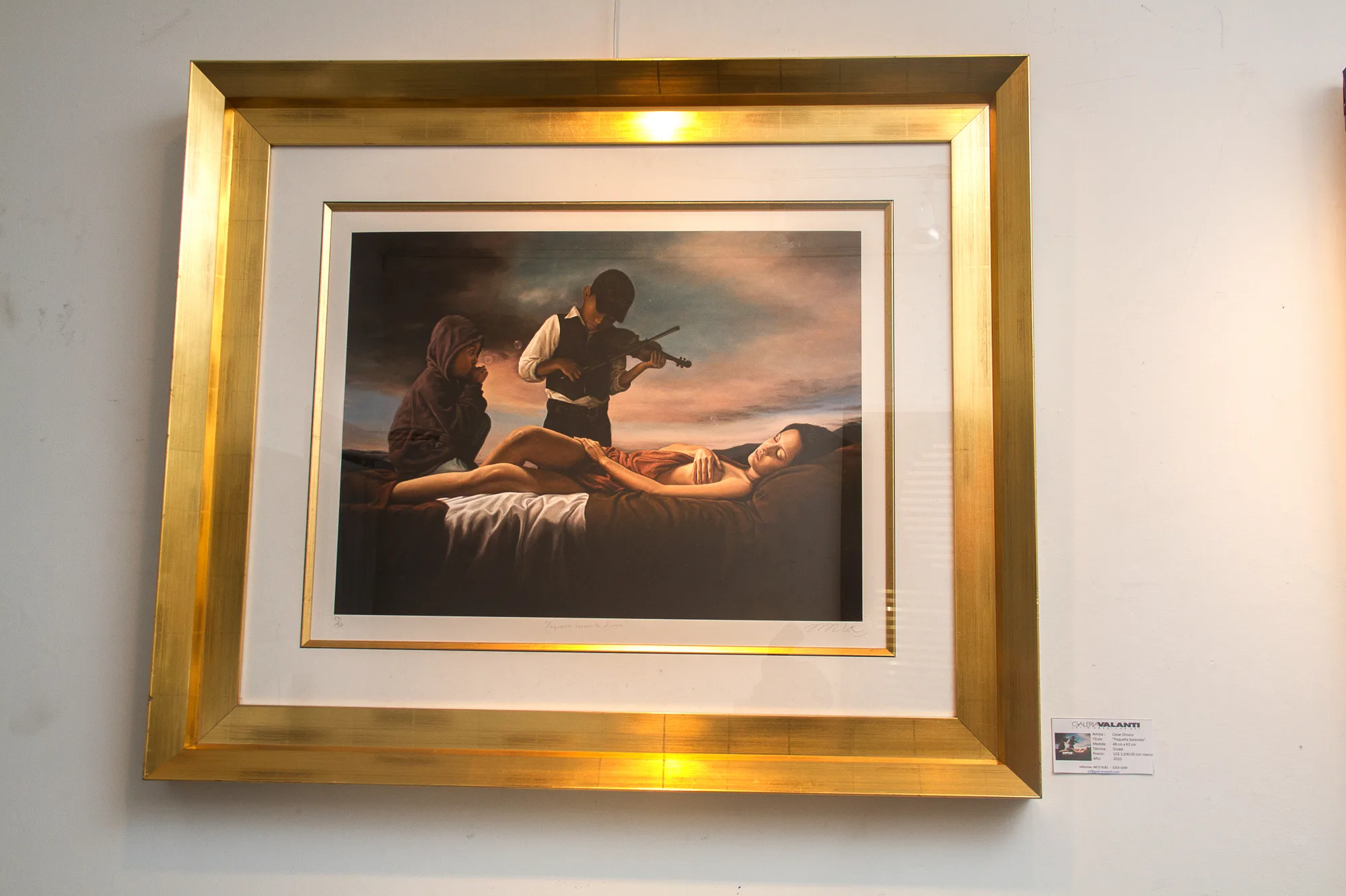 A work in a gilded frame with its label in a gallery room.